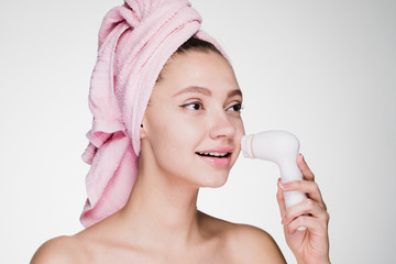 a cute young girl with a pink towel on her head makes a deep cleansing of the facial coding using...