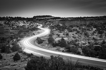 Black and white headlights on desert roadway