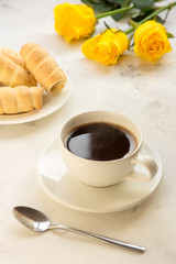 Coffee and sweet bakery on a white table, yellow roses on a background