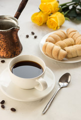Coffee, jezva and sweet bakery on a white table, yellow roses on a background