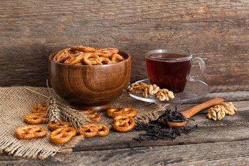 Tea in a cup, nuts and cracker on a wooden background