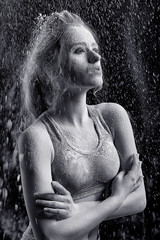 Athletic girl with flour on the body hands crossed on the chest with thrown flour on black background black and white image