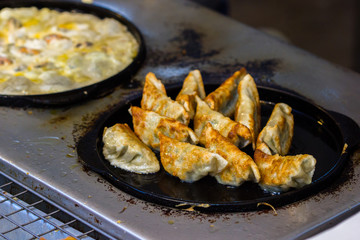 Nice to eat fried Dumplings on hot black pan. Ready to eat. Asian food background.