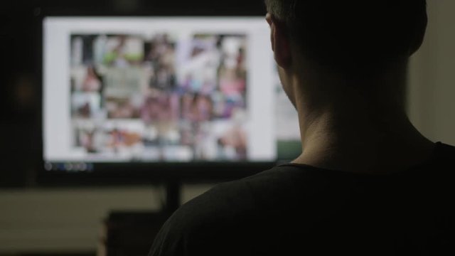 young man watching surfing pornography site on the web at night at home