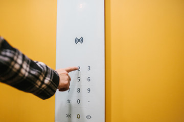 A woman clicks on an electronic button in a modern elevator. Inside the elevator.
