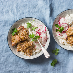 Slow cooker pork  with rice pilaf and radish salad on a blue background, top view