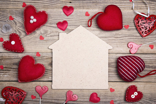 Home symbol with red hearts on wooden background with copy space.