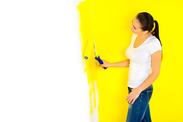 girl paints a roller against a wall in a room, repairs in the house