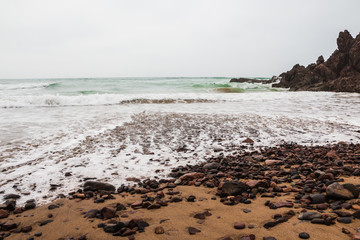 Coast, waves and beach with yellow sand and pebbles