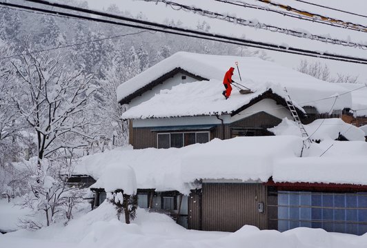 屋根の雪下ろしをする日本人