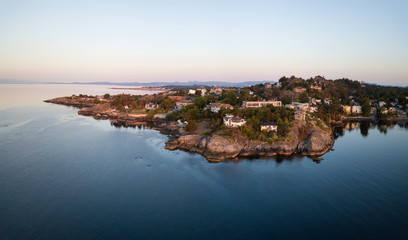 Aerial panorama of beautiful and luxury homes on the rocky coast during a vibrant sunrise. Taken in Victoria, Vancouver Island, BC, Canada.
