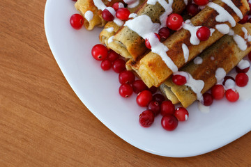 Traditional sweet rolled pancakes with poppy seeds on the plate top view