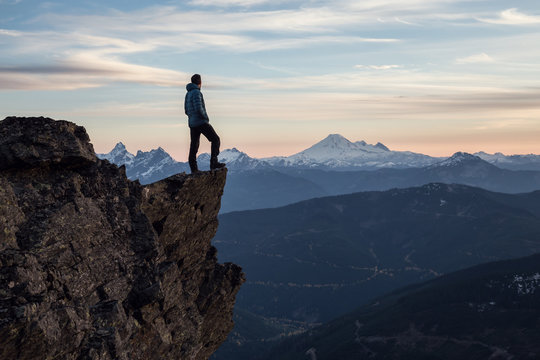 Adventurous man on top of the mountain during a vibrant sunset. Taken on Cheam Peak, near Chilliwack, East of Vancouver, British Columbia, Canada.