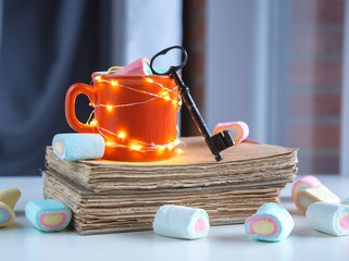 Cup of coffee with marshmallows and books with key