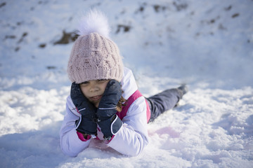 Fototapeta na wymiar A cute little girl plays on snow. Copy negative space. Selective focus