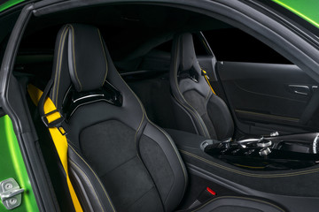 Modern Luxury sport car inside. Interior of prestige car. Leather seats with yellow stitching. Black perforated leather. Modern car interior details. Automatic gear stick shift. Media control Buttons