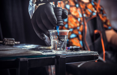 Hand of master of the art of tattooing with a tattoo gun.