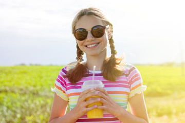 Happy girl drinking orange juice at hot summer day.