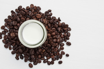 Coffee beans and milk in glass on white background