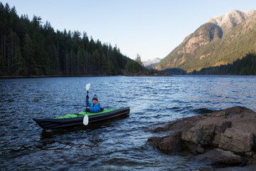 Fototapeta na wymiar Girl Kayaking in a Lake. Taken in Buntzen Lake, Vancouver, British Columbia, Canada.