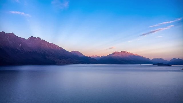Wakatipu Lake Sunrise time lapse with the mountains slowly lighten up by the first sun rays of the day -View from Bennett's Bluff Lookout in New Zealand.