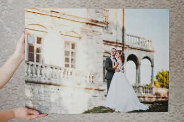 Fototapeta na wymiar Female hands holding huge wedding photo on the grey background.