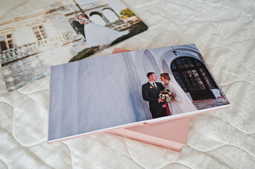 Pages with wedding photos of a photobook or photo album on bed.