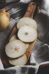 Close-up of pear's slices on a wooden board in rustic kitchen.