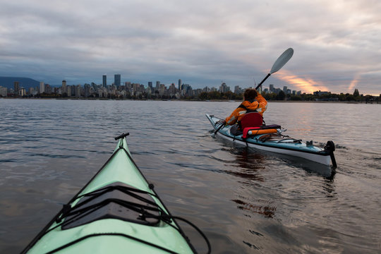 Adventure woman kayaking on a sea kayak in Vancouver, British Columbia, Canada. Taken during a cloudy sunrise.
