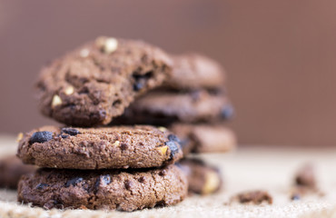 Chocolate chip cookies stacked on sackcloth background.