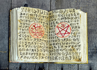 Open magic book with evil symbols and pentagram on shabby pages. Occult, esoteric, divination and...