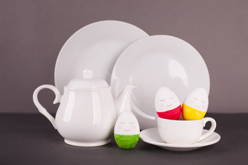 set of white utensils for Easter tea drinking and decorative cheerful eggs. Spring home concept