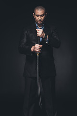 man in suit with japanese katana sword on black