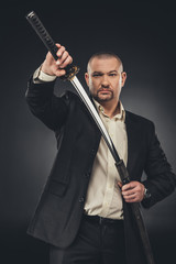 man in suit taking of his katana sword on black