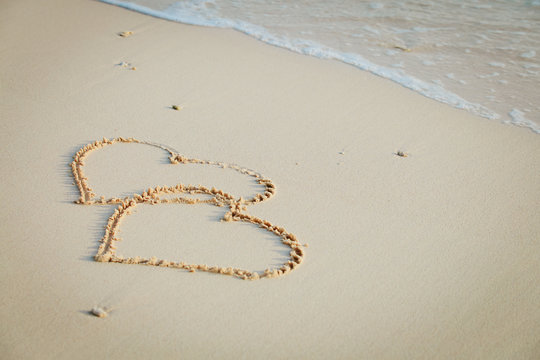 two hearts drawn on sand beach