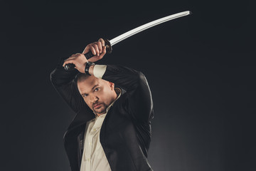 mature yakuza member in suit with katana sword isolated on black
