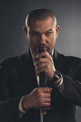 close-up portrait of adult man in suit with katana sword on black