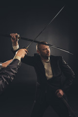 strong mature businessman fighting with katana sword isolated on black