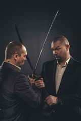 businessmen fighting with katana swords isolated on black