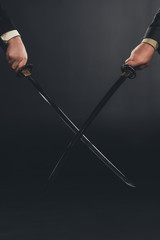 cropped shot of businessmen fighting with katana swords isolated on black