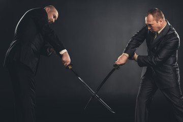 businessmen fighting with katana swords isolated on black