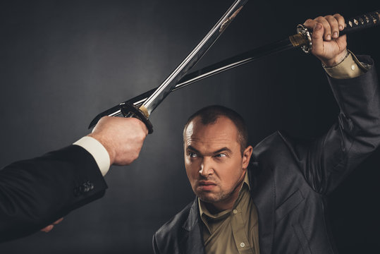 Cropped Shot Of Modern Samurai Fighting With Swords On Black