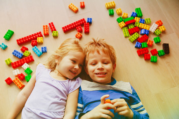 cute little boy and girl playing with plastic blocks