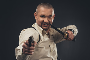 dangerous smiling man with knife and gun looking at camera