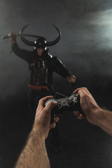 cropped shot of man controlling samurai character with gamepad on black
