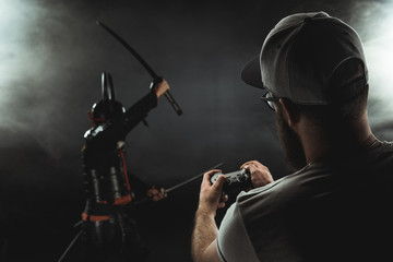 man controlling samurai character with gamepad on black