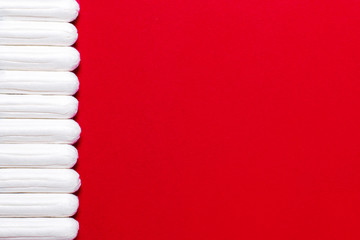 Menstruation, protection means. Row of white tampons on red background