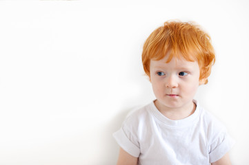 Pensive redhead boy on a white background