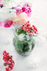 Obraz na płótnie Canvas Cooling mint detox water with a branch of viburnum and a bouquet of pink and white peonies on pastel pink background.