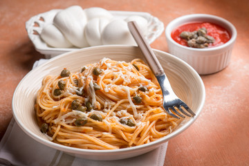 spaghetti with mozzarella tomato and capers, selective focus
